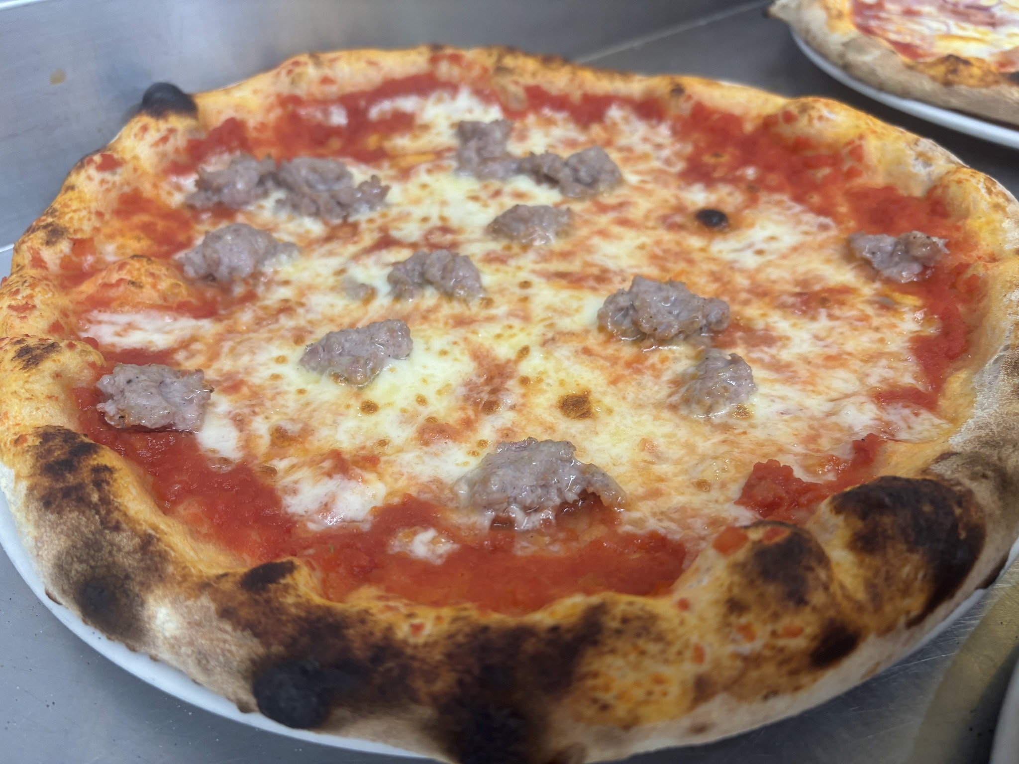 Pizza con mozzarella, pomodoro e salsiccia appena sfornata